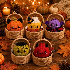 May include: Five crocheted Halloween-themed plush figures, each nestled in a round tan basket. The figures include an orange pumpkin cat, a candy corn witch with a broom, a purple vampire, a green Frankenstein monster, and a red devil.