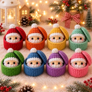 Könnte beinhalten: Acht gehäkelte Weihnachtsmannfiguren, jede in einem passenden runden Behälter mit Deckel. Die Figuren haben weiße Bärte, rosa Wangen und Mützen mit weißen Bommeln und sind in den Farben Rot, Orange, Gelb, Mint, Grün, Blau, Violett und Pink gehalten.