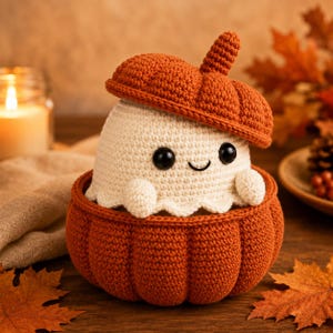 Peut inclure: Une figurine fantôme crochetée de couleur crème avec des yeux en perles noires et un petit sourire, nichée dans un contenant rond et côtelé en forme de citrouille orange. Le fantôme porte un couvercle assorti en forme de citrouille.