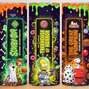 May include: Three cylindrical tumblers featuring Halloween-themed graphics. The first shows Scooby-Doo and Shaggy with ghosts and bones. The second displays The Simpsons Treehouse of Horror with Homer as an alien. The third features Peanuts characters.