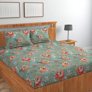 May include: A bed set featuring a teal green fitted sheet and two matching pillowcases, all decorated with a repeating floral pattern in shades of red, orange, yellow, and white, set against a wooden bed frame with a headboard.