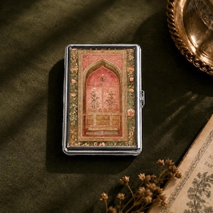 May include: A rectangular silver metal case featuring a decorative inlay on the front. The inlay displays a pink arched architectural motif with floral details, surrounded by a green border with intricate botanical patterns and small flowers.