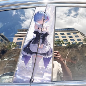 Op de afbeelding: Een verticale autoruitsticker met een anime-figuur met kort blauw haar, gekleed in een zwart-wit dienstmeisjeskostuum met een geschulpt schort, witte kniekousen en donkere schoenen, staand tegen een lichte achtergrond.