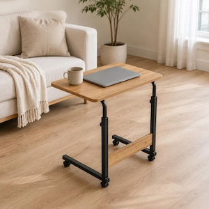 May include: A rectangular side table with a light wood grain top and a black metal frame. The table features an adjustable height mechanism, a horizontal support bar, and four small caster wheels at the base for mobility on the floor.