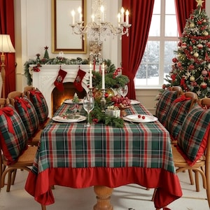 Puede incluir: Una mesa de comedor preparada para una comida festiva, con un mantel de cuadros verdes, rojos y blancos con un borde de volantes rojo sólido. La mesa está rodeada de sillas de madera con cojines de cuadros, cada uno con un lazo rojo.