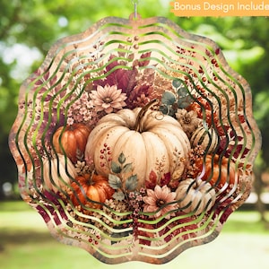 May include: A circular metal wind spinner featuring a fall-themed design with white and orange pumpkins, autumn leaves, and berries. The scalloped-edge ornament includes a hanging loop at the top and the text Bonus Design Included.