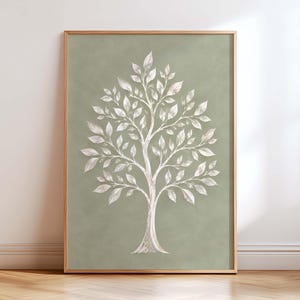Op de afbeelding: Een ingelijste wandkunstprint met een gestileerde boom met witte, getextureerde bladeren en takken, gecentreerd tegen een effen, gedempte saliegroene achtergrond. Het kunstwerk zit in een dunne, lichtgekleurde houten lijst met een rand.