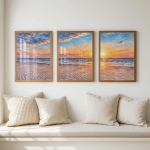 Könnte beinhalten: Ein Triptychon aus drei gerahmten Wandbildern, die einen Küstensonnenuntergang mit Sandstrand, Meereswellen und einem farbenfrohen Himmel zeigen. Jeder rechteckige Druck ist in einem hellbraunen Holzrahmen gefasst und zeigt den Horizont.