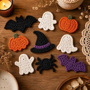 May include: A collection of nine crocheted Halloween-themed appliques including two orange pumpkins, three white ghosts, one black bat, one purple bat, one black witch hat with a purple band, and one black spider, all arranged on a wooden surface.