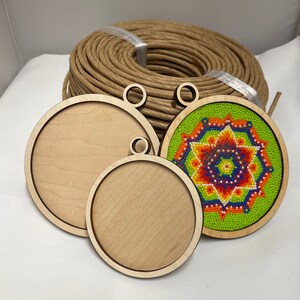 K&ouml;nnte beinhalten: Drei runde Holzornamente mit einem Loch oben zum Aufh&auml;ngen. Das gr&ouml;&szlig;te Ornament ist leer, das mittlere Ornament ist leer und das kleinste Ornament hat ein buntes Perlenmuster.