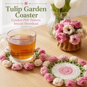 Könnte beinhalten: Zwei runde Häkeluntersetzer mit einem zentralen kreisförmigen Design in Weiß und Rosa, umgeben von einer Bordüre aus kleinen, dreidimensionalen rosa und cremefarbenen Tulpenblüten mit grünen Stielen. Ein Untersetzer trägt eine klare Glastasse.