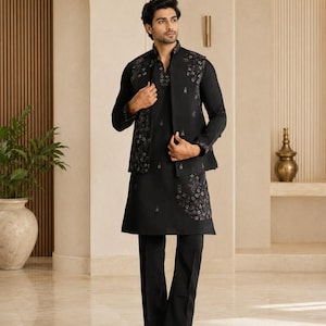 May include: A black long-sleeved kurta paired with matching black trousers and a sleeveless vest. The vest and the lower portion of the kurta feature intricate dark floral embroidery. The ensemble is completed with black formal shoes.