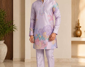 May include: A light lavender long-sleeved kurta with a mandarin collar and matching straight-leg trousers. The garment features intricate embroidery around the neckline and a colorful, abstract floral pattern in shades of pink, blue, and green.