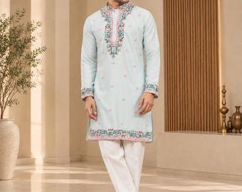 May include: A light blue long-sleeved kurta featuring a mandarin collar and intricate floral embroidery in pink, green, and white around the neckline, cuffs, and hem, paired with plain white trousers and matching white slip-on shoes.