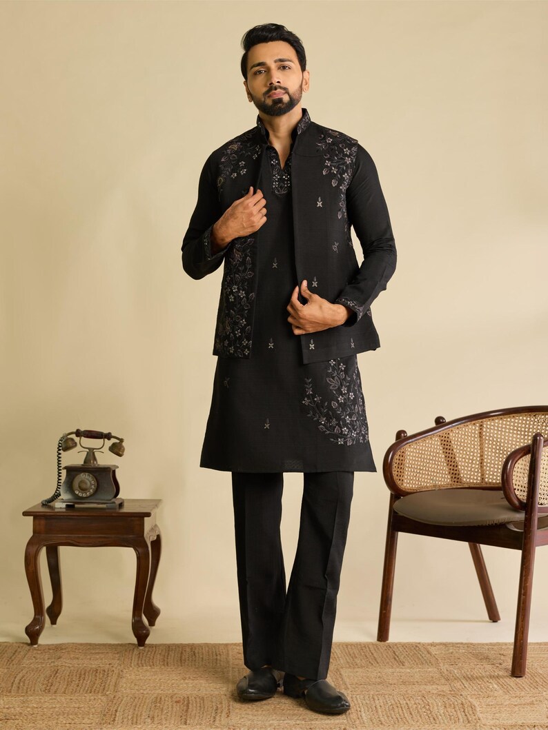 May include: A black long-sleeved kurta paired with matching black trousers and a sleeveless vest. The ensemble features intricate grey floral embroidery on the vest and the kurta hem. The vest has a high collar and the kurta has a V-neckline.