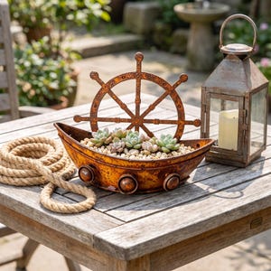 May include: A boat-shaped planter with a rusted metal finish, featuring a ship's wheel attachment and three circular side accents. The planter is filled with small green succulents and light-colored pebbles, accompanied by a coiled tan rope.