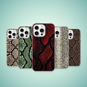 May include: Five smartphone cases arranged in a row, each featuring a distinct snakeskin pattern. The colours include tan, green, deep red, light grey, and dark brown. Each case has a cutout for a multi-lens camera system on the upper left corner.