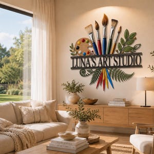 以下が含まれることがあります： LUNA'S ART STUDIOという文字が刻まれた金属製の壁掛け看板。木製の絵の具パレット、カラフルな持ち手の絵筆5本、緑の葉の装飾が左右対称に配置されています。