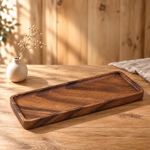 Può includere: Un vassoio rettangolare in legno con finitura marrone scuro e venature del legno visibili. Il vassoio presenta bordi leggermente rialzati e una superficie interna liscia e piatta, che mette in risalto la consistenza naturale del legno.