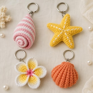 Può includere: Quattro portachiavi all'uncinetto con temi marini e floreali. Il set include una conchiglia a spirale a righe rosa e bianche, una stella marina gialla con cuciture bianche, un fiore bianco e giallo con centro rosa e una conchiglia arancione.