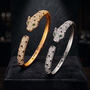 Peut inclure: Deux bracelets ouverts en forme de panthères. L'un est doré avec des pierres claires et des accents noirs, l'autre est argenté avec des pierres claires et des accents noirs. Les deux présentent des yeux en pierre verte et une conception articulée.