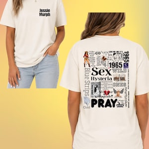 May include: A cream-colored t-shirt featuring the text Jessie Murph on the front left chest. The back displays a collage of various graphics and text including the words Sex, Hysteria, Wild, and Pray, alongside illustrations of a cowgirl and boots.
