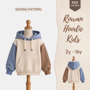 Puede incluir: Un patrón de costura en PDF para una sudadera con capucha de bloques de color etiquetada Rowan Hoodie Kids 2y-16y. La sudadera tiene un cuerpo color crema, capucha azul, manga derecha azul, manga izquierda marrón, bolsillo canguro y cordones.