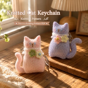 May include: Two knitted cat keychains, one light pink and one light purple, each featuring a small crocheted flower accent, embroidered facial features, and a metal keyring attachment. The text Knitted Cat Keychain Knitting Pattern is visible.