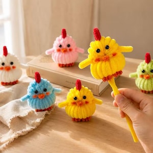 Puede incluir: Un conjunto de seis pequeñas figuras redondas y difusas con forma de pollo hechas de limpiapipas en blanco, rosa, amarillo, azul y verde claro. Cada figura tiene una cresta roja, un pico naranja y ojos negros. Un pollo amarillo está unido a un bolígrafo.