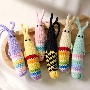 May include: Six handmade crochet shrimp toys in various colours including purple, yellow, pink, black, cream, and light blue. Each shrimp features two antennae, two small black bead eyes, and a striped or patterned tail section in vibrant colours.