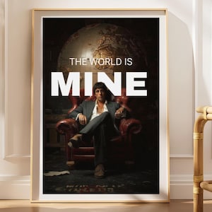 May include: A framed poster featuring a man in a dark suit sitting in a red leather armchair in front of a large globe. The text THE WORLD IS MINE is printed in white capital letters across the centre of the image, with MINE in a larger font.