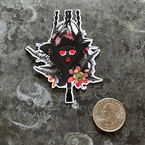 May include: Black and white sticker with a floral design and a creature with red eyes. The creature is surrounded by flowers and leaves.