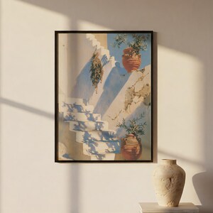 Könnte beinhalten: Ein gerahmter vertikaler Wandkunstdruck, der eine sonnendurchflutete mediterrane Szene mit weißen Steintreppen, zwei Terrakottatöpfen mit grünen Pflanzen und einem hängenden Bündel getrockneter Kräuter vor einer weißen Wand zeigt.