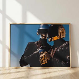 Peut inclure: Une impression d'art mural encadrée représentant deux personnages portant des vestes à sequins noirs et des casques robotiques. Un casque est argenté avec une visière sombre, l'autre est noir avec une plaque dorée. Le fond est un ciel bleu vif.
