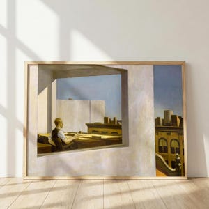 Puede incluir: Una impresión artística enmarcada que representa una pintura de una persona sentada en un escritorio dentro de una habitación con una ventana grande. La escena muestra una vista de tejados urbanos bajo un cielo despejado con sombras proyectadas.
