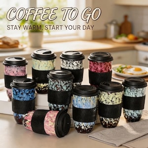 Könnte beinhalten: Eine Sammlung von zehn wiederverwendbaren Reisebechern mit schwarzen Deckeln und schwarzen Silikonmanschetten. Jeder Becher hat ein einzigartiges, mehrfarbig gesprenkeltes Muster. Der Text COFFEE TO GO und STAY WARM, START YOUR DAY ist sichtbar.