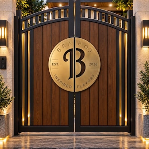 Puede incluir: Una puerta doble con paneles de madera oscura verticales enmarcados en metal negro con iluminación vertical integrada. Una gran placa circular de latón está centrada en la puerta, mostrando el texto BRA BOO, EST. 2026 y INSPIRED FLAVORS con una letra B grande.