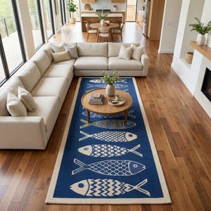 May include: A rectangular area rug featuring a deep blue background with a repeating pattern of stylised white fish, each decorated with unique geometric scales and chevron tail designs, finished with a solid cream-coloured border on all four sides.