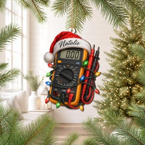 May include: A hanging ornament shaped like a yellow and black digital multimeter wearing a red and white Santa hat with the name Natalie printed on the brim. The device is wrapped in a string of colorful Christmas lights with red and black probes.