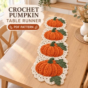 Könnte beinhalten: Ein gehäkelter Tischläufer mit vier orangefarbenen Kürbissen mit grünen Stielen und Blättern auf einer cremefarbenen Spitzenbordüre. Der Text CROCHET PUMPKIN TABLE RUNNER PDF PATTERN steht in der oberen linken Ecke des Bildes.