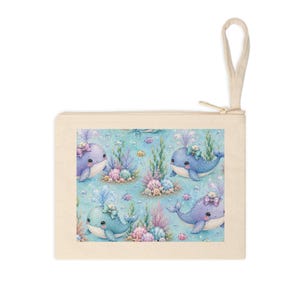 May include: A rectangular off-white canvas zipper pouch with a wrist strap. The center features a repeating pattern of blue cartoon whales with bows, colorful coral, seashells, and small fish on a light blue background with bubbles.