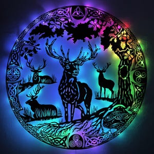 May include: A circular black metal wall art piece featuring a forest scene with four deer, oak trees, and Celtic knotwork borders. The design is illuminated from behind by multi-colored LED lights that cast blue, purple, and green hues.
