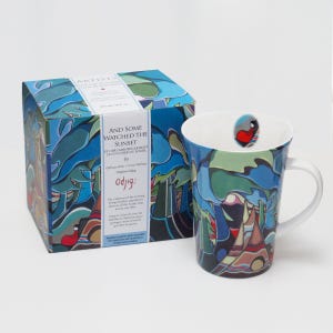 May include: A ceramic mug and its matching box featuring a colourful abstract landscape design with blue, green, and brown tones. The box displays the text AND SOME WATCHED THE SUNSET by Daphne Odjig, and the mug has a small red bird icon inside.