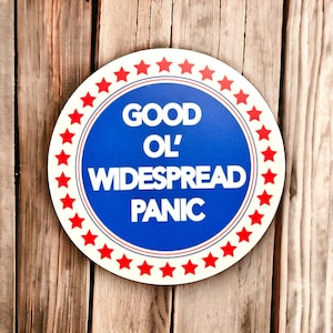 May include: A round, blue and white sign with red stars around the border. The sign says "Good Ol' Widespread Panic" in white letters.