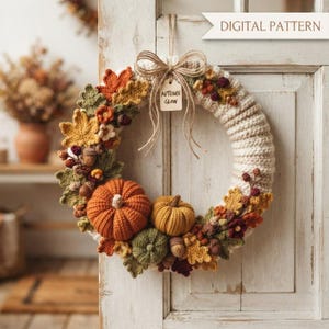 Peut inclure: Une couronne au crochet avec une base couleur crème ornée de citrouilles orange, jaunes et vertes, de feuilles d'automne et de petites baies. Un nœud en ficelle de jute est suspendu avec une étiquette "AUTUMN GLOW". Le texte "DIGITAL PATTERN" est visible.