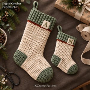 Könnte beinhalten: Zwei gehäkelte Weihnachtsstrümpfe in Creme, Salbeigrün und Rostorange. Der größere Strumpf zeigt den Buchstaben A, der kleinere den Buchstaben M auf quadratischen Aufnähern. Text: Digital Crochet Pattern PDF und IKCrochetPatterns.