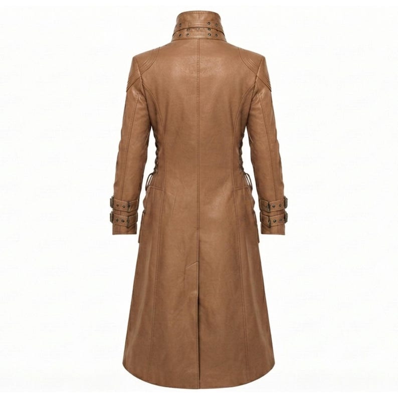 May include: A tan long-length coat featuring a high collar with decorative studs, long sleeves with buckled straps at the cuffs, and a central back vent. The garment is constructed with structured seams and a smooth finish throughout the design.