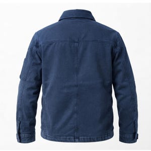 May include: A dark blue jacket featuring a classic collar, long sleeves with buttoned cuffs, and a structured back panel with vertical stitching. The garment is made of a durable, textured fabric and includes a small utility pocket on the sleeve.