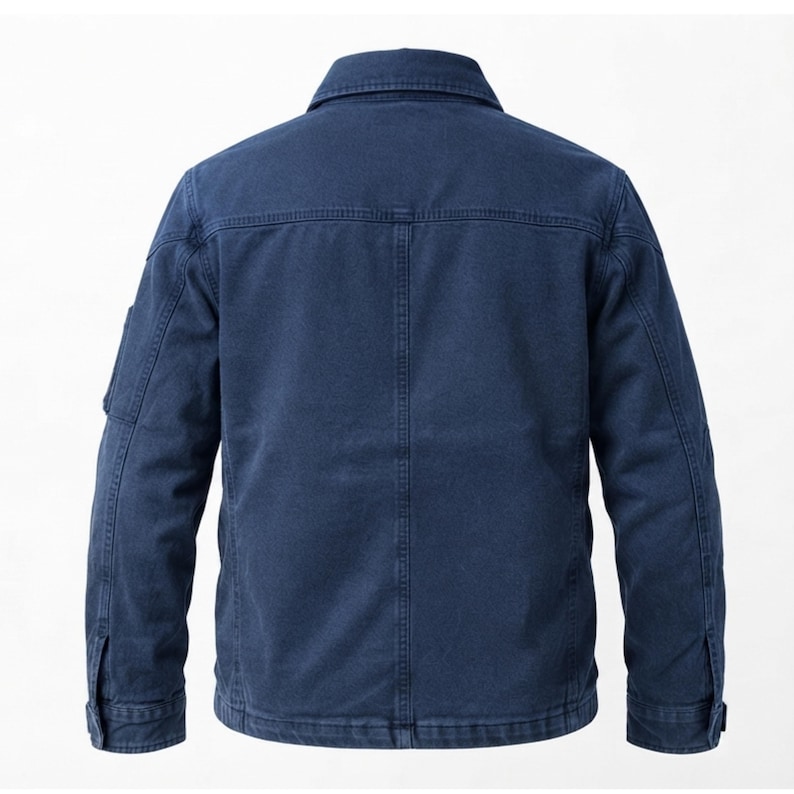 May include: A dark blue jacket featuring a classic collar, long sleeves with buttoned cuffs, and a structured back panel with vertical stitching. The garment is made of a durable, textured fabric and includes a small utility pocket on the sleeve.