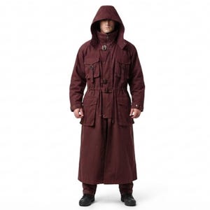 Peut inclure: Un long manteau &agrave; capuche bordeaux fonc&eacute; dot&eacute; d'un col montant, d'une fermeture &eacute;clair frontale et de multiples poches utilitaires &agrave; boucles. Le v&ecirc;tement comprend un cordon de serrage &agrave; la taille et des manches longues &agrave; poignets boutonn&eacute;s.